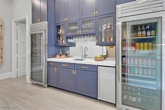 bar with blue cabinets, sink, stainless steel refrigerator, and built in refrigerator