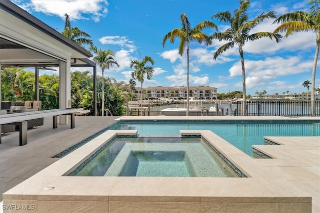 view of swimming pool featuring a patio area, an in ground hot tub, and a water view