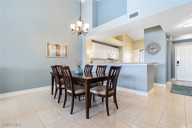 dining area with light tile patterned floors, high vaulted ceiling, and an inviting chandelier