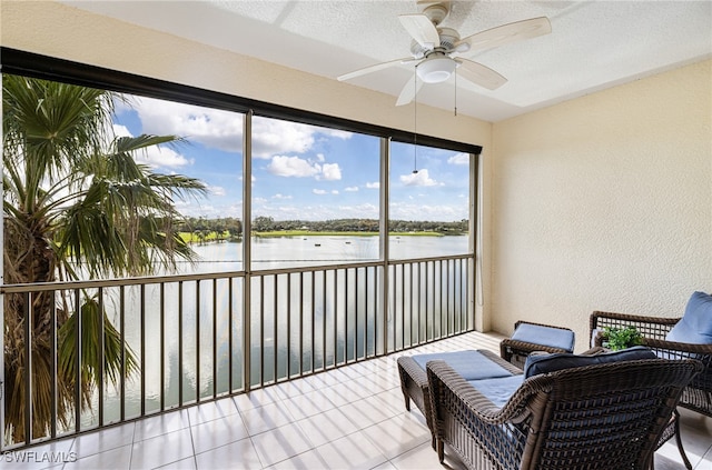 sunroom with ceiling fan and a water view