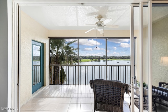 sunroom with ceiling fan and a water view