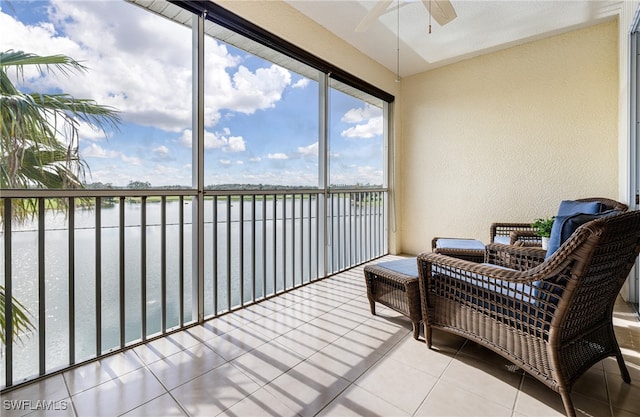 sunroom with ceiling fan and a water view