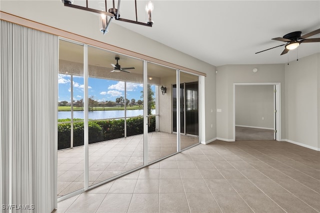 spare room featuring light tile patterned floors, ceiling fan with notable chandelier, and a water view