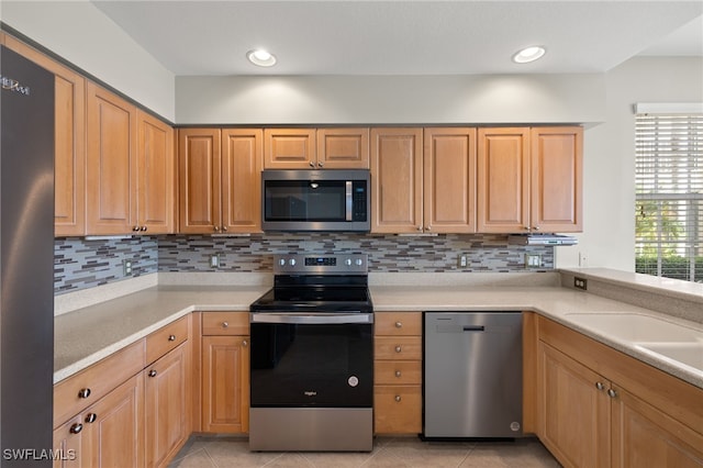 kitchen featuring backsplash, light tile patterned floors, and stainless steel appliances