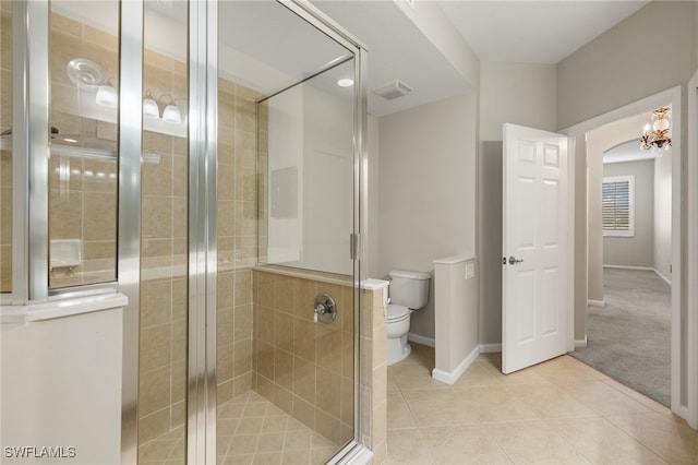 bathroom with tile patterned flooring, a shower with shower door, and toilet