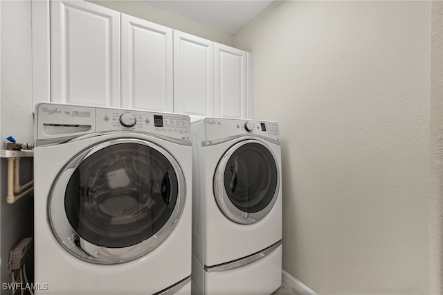 clothes washing area with cabinets and separate washer and dryer