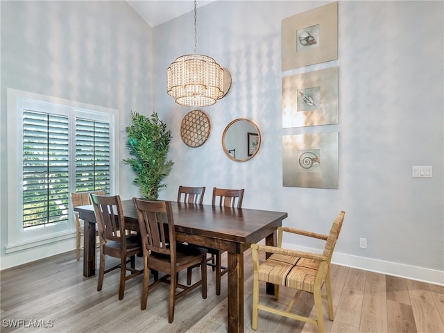 dining space with hardwood / wood-style flooring, high vaulted ceiling, and a notable chandelier