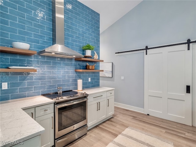 kitchen with a barn door, white cabinetry, light hardwood / wood-style floors, and stainless steel electric range