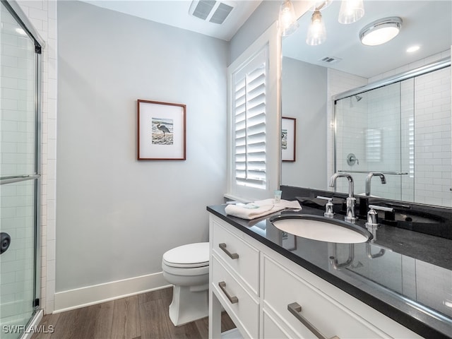 bathroom featuring hardwood / wood-style floors, vanity, a shower with door, and toilet