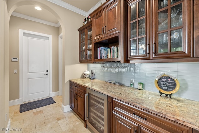 bar with decorative backsplash, light stone countertops, crown molding, and beverage cooler