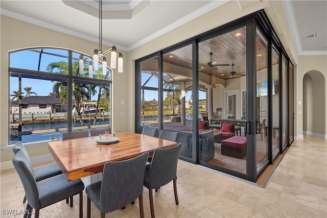 dining room with a towering ceiling, a water view, ceiling fan, and ornamental molding