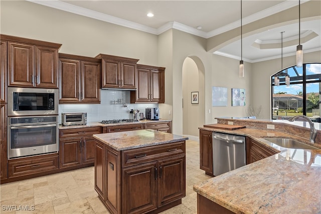 kitchen featuring appliances with stainless steel finishes, a center island, light stone counters, and sink