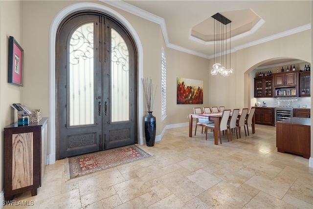 entrance foyer featuring french doors, an inviting chandelier, wine cooler, and ornamental molding