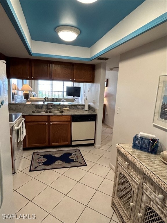 kitchen with white appliances, sink, light tile patterned flooring, and a raised ceiling