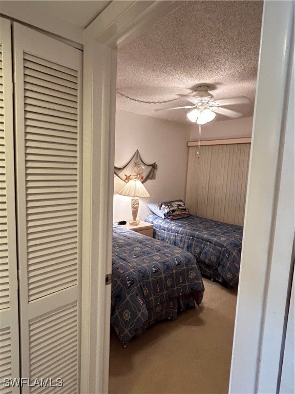 bedroom with ceiling fan, a textured ceiling, and carpet flooring