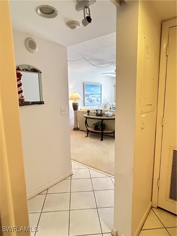 hallway with a textured ceiling and light tile patterned floors