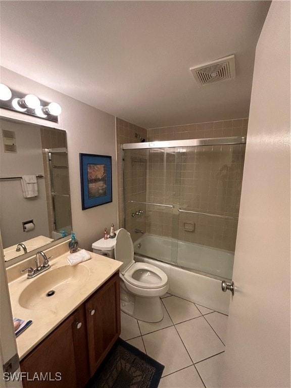 full bathroom featuring vanity, bath / shower combo with glass door, tile patterned flooring, and toilet