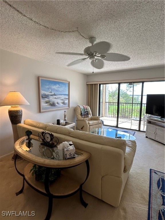 living room featuring ceiling fan, a textured ceiling, and light colored carpet