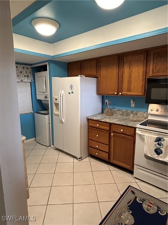 kitchen featuring stacked washing maching and dryer, white appliances, and light tile patterned floors