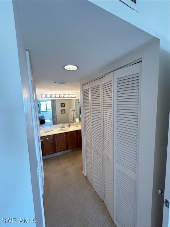 hall featuring sink and light carpet