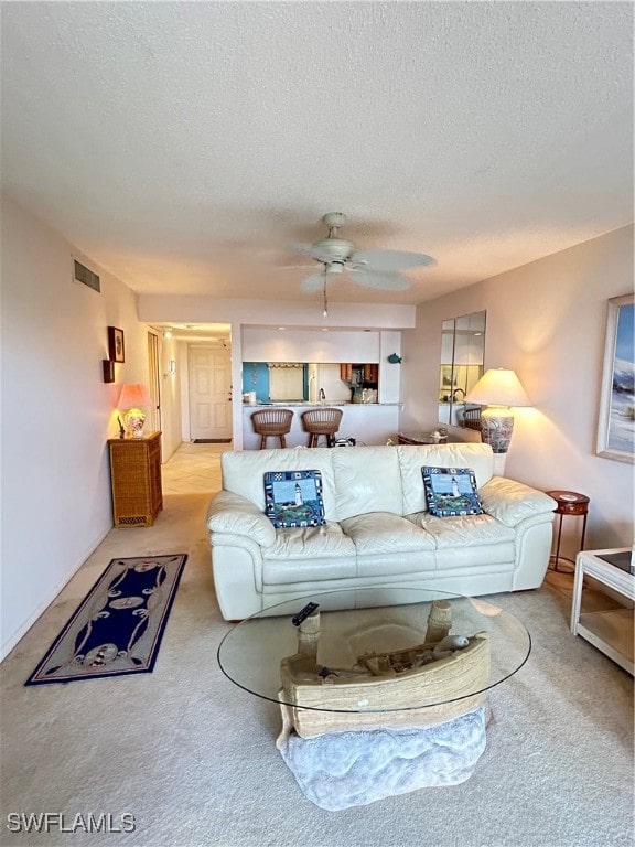 carpeted living room with a textured ceiling and ceiling fan