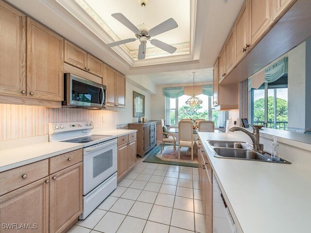 kitchen with sink, light brown cabinets, decorative light fixtures, white appliances, and a tray ceiling