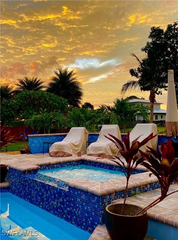 pool at dusk featuring a patio area