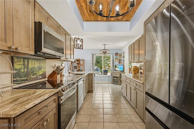 1857 Whitecap Cir, North Fort Myers, FL 33903 - kitchen featuring stainless steel appliances, a tray ceiling, a chandelier, a sink, and hanging light fixtures