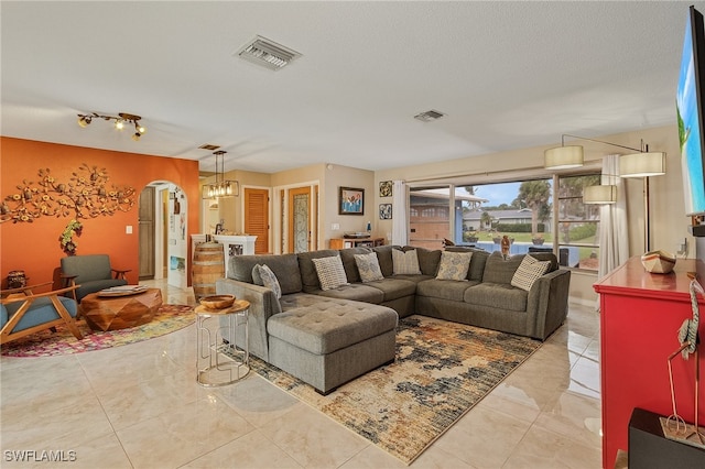 living room featuring light tile patterned flooring, a chandelier, and a textured ceiling