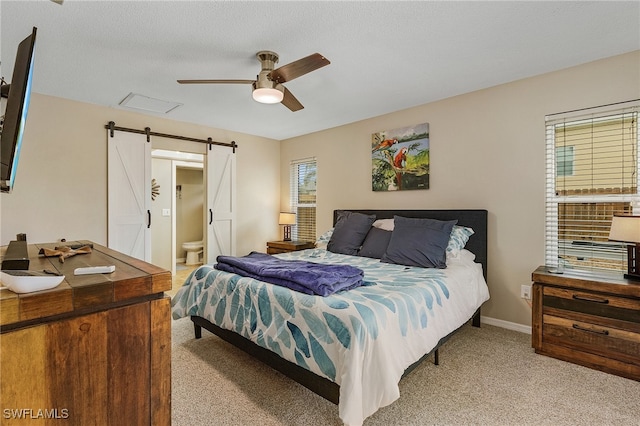 bedroom with a textured ceiling, a barn door, light colored carpet, ceiling fan, and ensuite bathroom