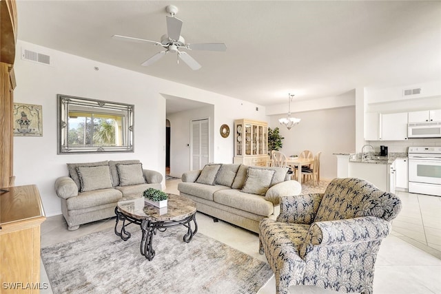 living room with ceiling fan with notable chandelier and light tile patterned floors