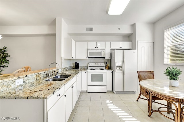 kitchen with white appliances, light stone countertops, kitchen peninsula, white cabinetry, and sink