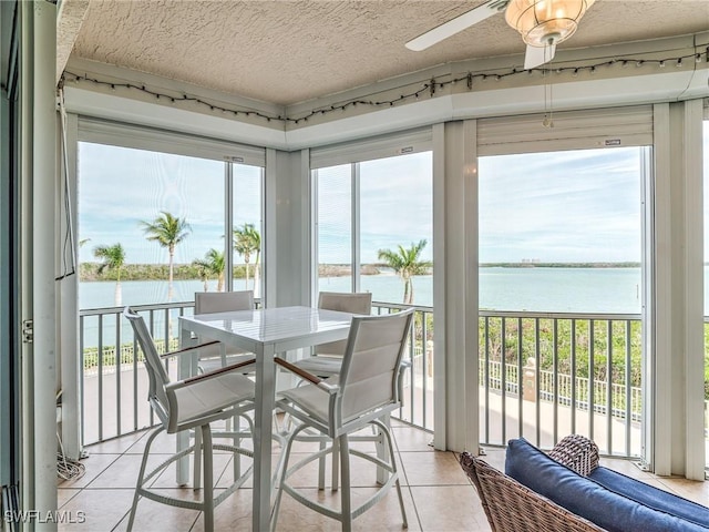 sunroom / solarium featuring a water view and ceiling fan