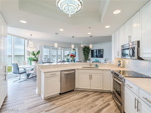 4137 Bay Beach Ln Unit 532, Fort Myers Beach, FL 33931 - kitchen with appliances with stainless steel finishes, a tray ceiling, a sink, recessed lighting, and a peninsula