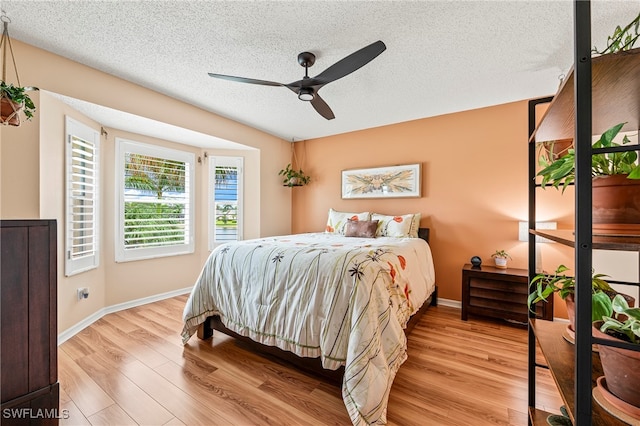 bedroom featuring ceiling fan, light hardwood / wood-style flooring, and a textured ceiling