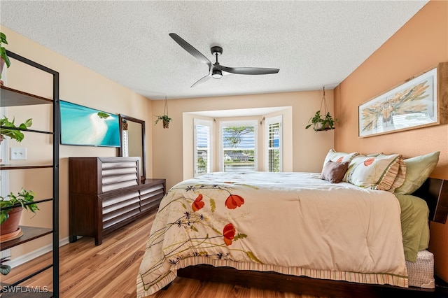 bedroom featuring a textured ceiling, light hardwood / wood-style flooring, and ceiling fan