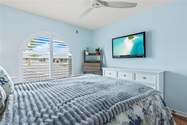 bedroom featuring ceiling fan, hardwood / wood-style floors, and a textured ceiling