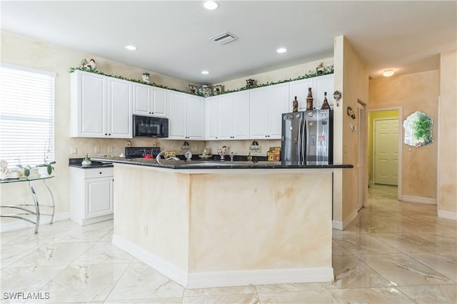 kitchen featuring white cabinetry, a kitchen island with sink, and stainless steel refrigerator