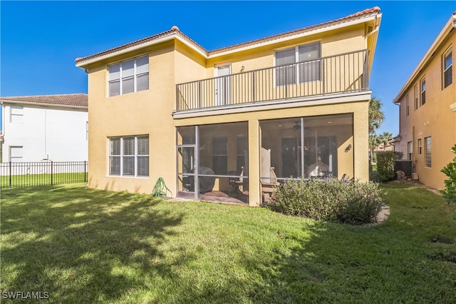 back of property featuring a lawn, a sunroom, and a balcony