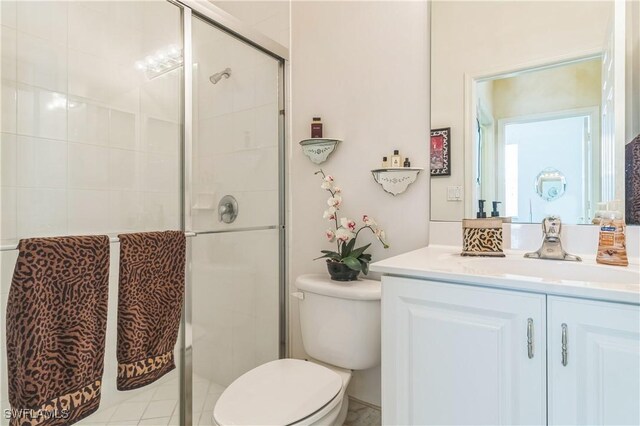 bathroom with vanity, toilet, and a shower with door