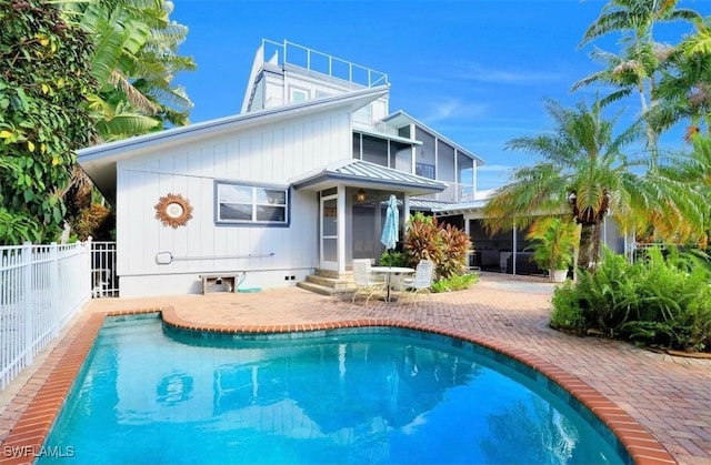 rear view of property with a patio, a fenced in pool, and a sunroom