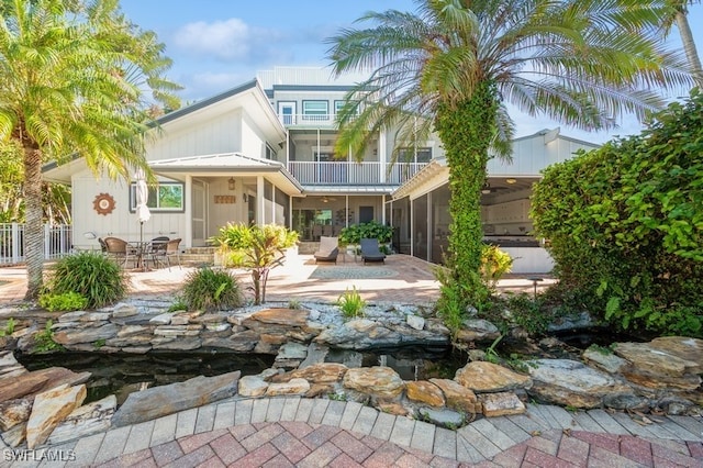 back of property featuring a sunroom, a balcony, and a patio