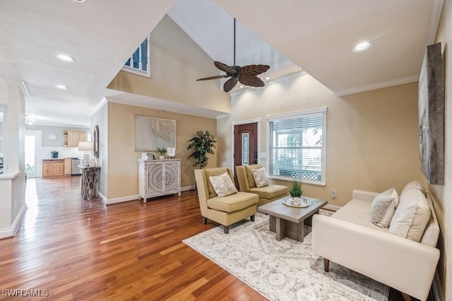 living room with ceiling fan, crown molding, a towering ceiling, and wood-type flooring