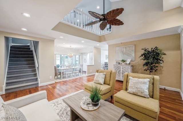 living room featuring hardwood / wood-style floors, ceiling fan with notable chandelier, and crown molding