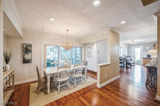 dining area featuring dark wood-type flooring, a healthy amount of sunlight, and a notable chandelier