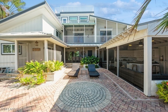 rear view of property with ceiling fan, a patio, and an outdoor living space