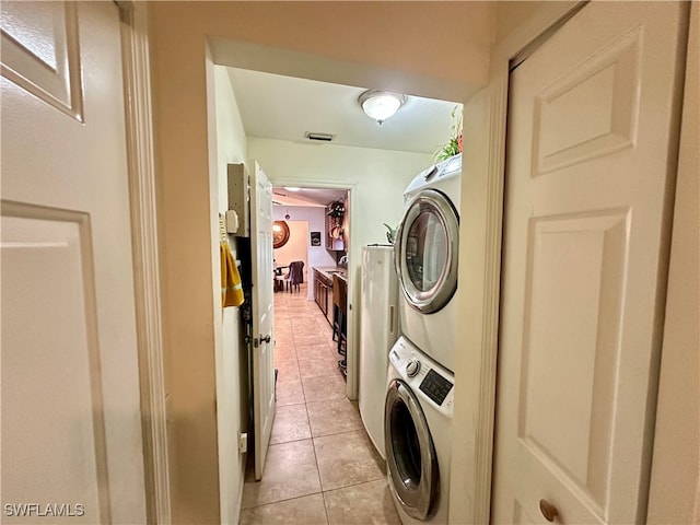 washroom with stacked washing maching and dryer and light tile patterned flooring