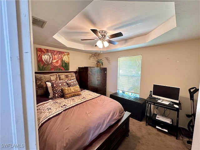 carpeted bedroom featuring ceiling fan and a raised ceiling