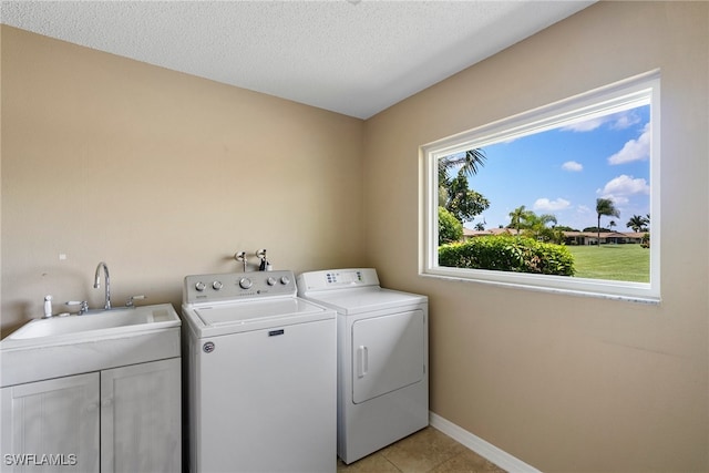 washroom with light tile patterned floors, sink, a textured ceiling, and washing machine and clothes dryer