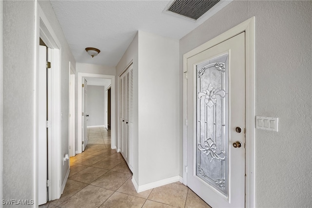 entryway featuring a textured ceiling and light tile patterned flooring